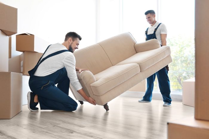 Delivery-men-moving-sofa-in-room-at-new-home